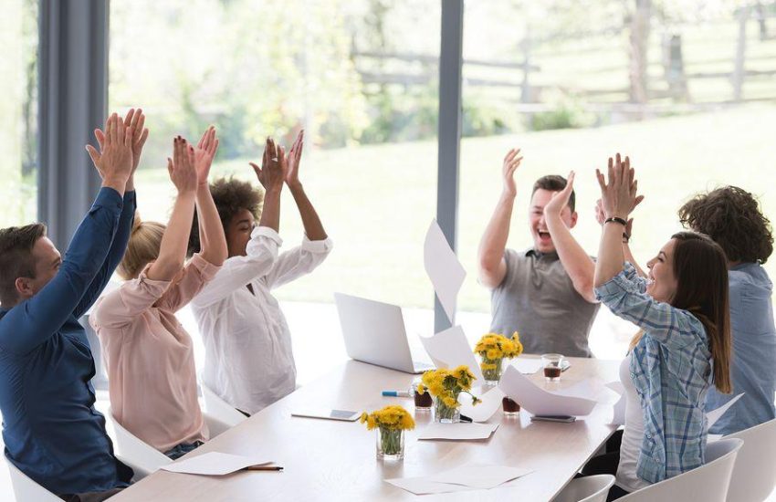multiethnic Group of young business people throwing documents and looking happy while celebrating success at their working places in startup office