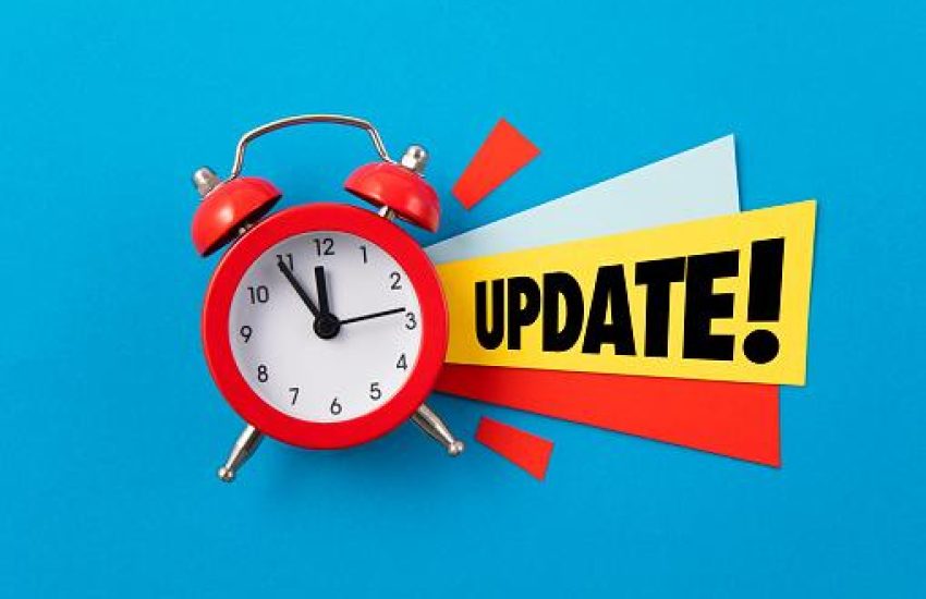 Red alarm clock with colored papers and update text on blue background